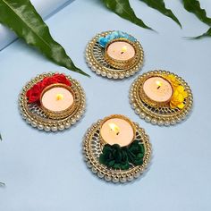 three small candles with flowers on them are sitting next to some leaves and greenery