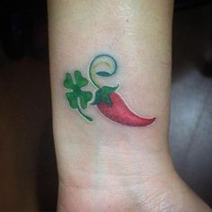 a small red pepper with shamrock leaves on the side of the wrist tattoo design for women