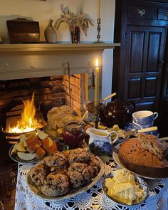 a table topped with cakes and pies next to a fireplace