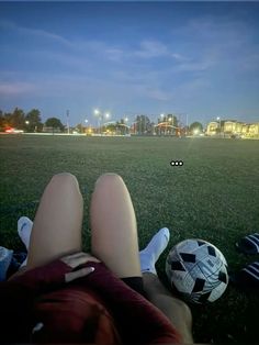 two people are sitting on the grass with soccer balls