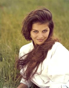 a woman with long hair sitting in the grass