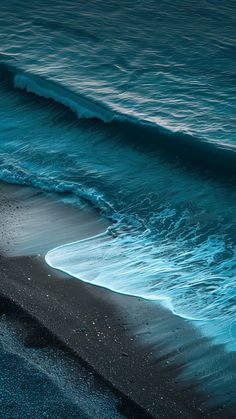 the ocean waves are rolling in and out of the water on the black sand beach