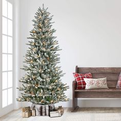 a white christmas tree in a living room next to a wooden bench