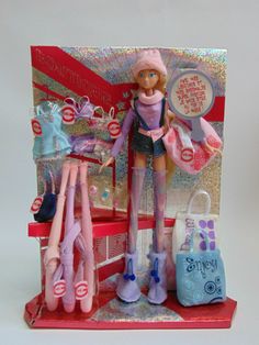 a barbie doll is standing in front of a display case with many items on it