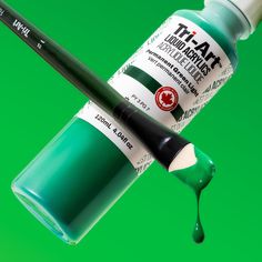 a bottle of paint and a brush on a green background