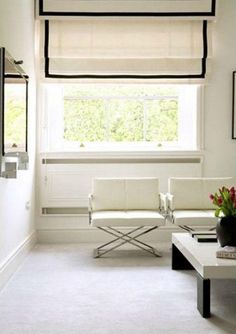 a living room with two white chairs and a coffee table in front of a window