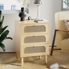 a wooden cabinet with three drawers and a lamp on top in a living room next to a chair