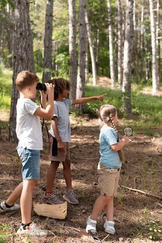 three children are looking through binoculars in the woods