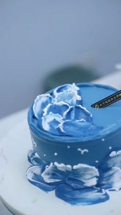 a blue cake with white icing on it sitting on top of a countertop