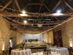 the inside of a barn with tables and chairs set up for a formal dinner or function