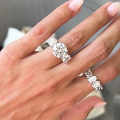 a woman's hand with three diamond rings on her left and the other hand holding an engagement ring