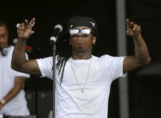 a man in white shirt and black hat on stage with his hands up to the side