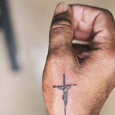 a hand with a cross tattoo on it