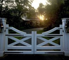 the sun is setting behind a white gate with two lanterns on it's sides