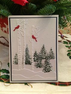 a christmas card with trees and birds in the snow, on top of a table