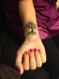 a woman's hand with a tree tattoo on it