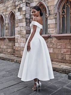 a woman in a white dress is standing outside