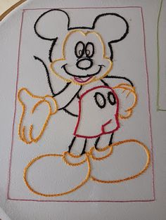 an embroidered mickey mouse on a white plate with red and yellow stitching around it