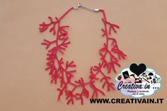 a red necklace is displayed on a beige surface with a black heart and the words creative in it