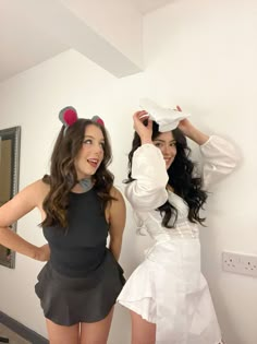 two women dressed in costumes standing next to each other, one wearing a mouse ears hat