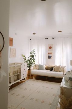 a baby's room with a couch, crib and window