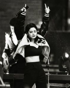 a black and white photo of a woman with her arms in the air while standing on a stage