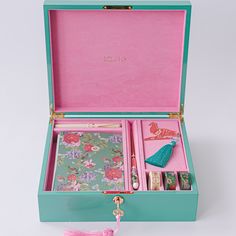 a pink and blue box with various items in it sitting on a table next to a tassel