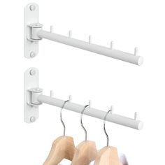 two white clothes hangers and one is hanging on the wall