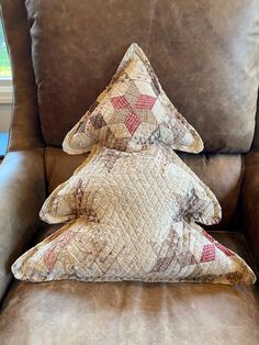 a brown leather chair with two decorative pillows on it's back and the seat up