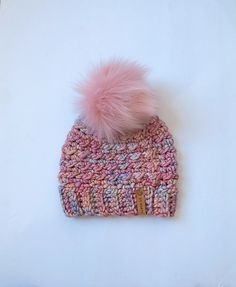 a knitted hat with a pink pom - pom on top of it