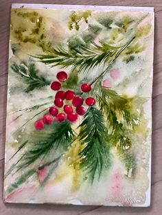 a watercolor painting of red berries and green leaves on a white paper with wood flooring