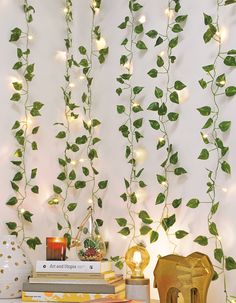 the wall is decorated with green leaves and string lights, along with books on a table