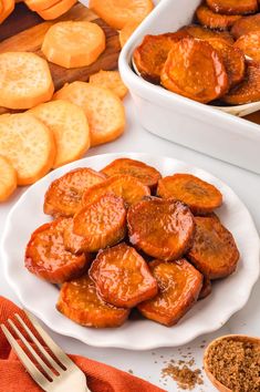 two white plates filled with sweet potatoes next to some sliced oranges and cinnamon sticks