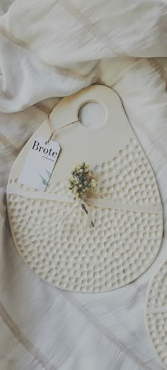 a close up of an object on a bed with a white sheet and some flowers