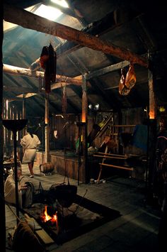 an old barn with wood burning in the fireplace and horses hanging from the rafters