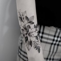 a black and white photo of a flower on the left arm with leaves around it