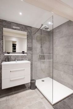 a bathroom with a walk in shower next to a white sink and mirror on the wall