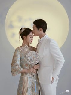 a man and woman are standing in front of a full moon with their heads touching each other