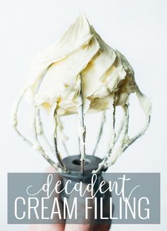 a hand holding a whisk with cream filling on it and the words, decadent cream filling