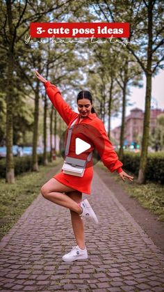 a woman is dancing in the middle of a brick path with trees and bushes behind her