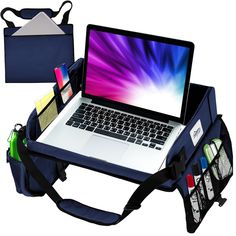 an open laptop computer sitting on top of a blue bag next to other office supplies