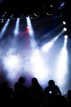 people are standing in front of bright lights at a concert