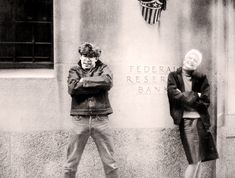 two people standing next to a wall with the words federal reserve bank on it's side