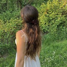 a woman with long hair standing in the grass