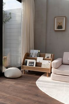 a living room with a couch, chair and book shelf in front of a window