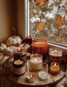 candles and pumpkins on a table in front of a window