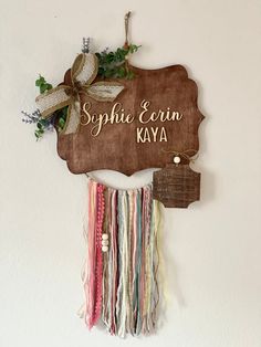 a wooden sign hanging from the side of a wall with ribbons on it's sides