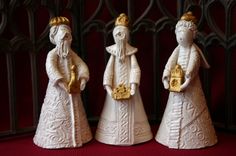 three white figurines with gold crowns on them