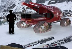 a man standing next to a red vehicle on top of snow covered ground