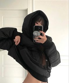 a woman taking a selfie in front of a mirror wearing a black hoodie